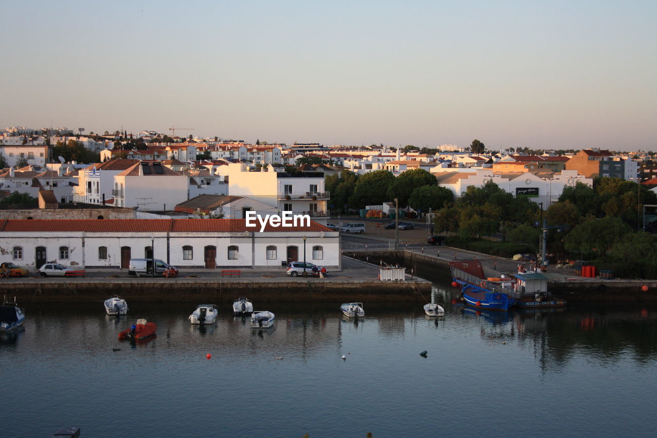 Buildings by river against clear sky