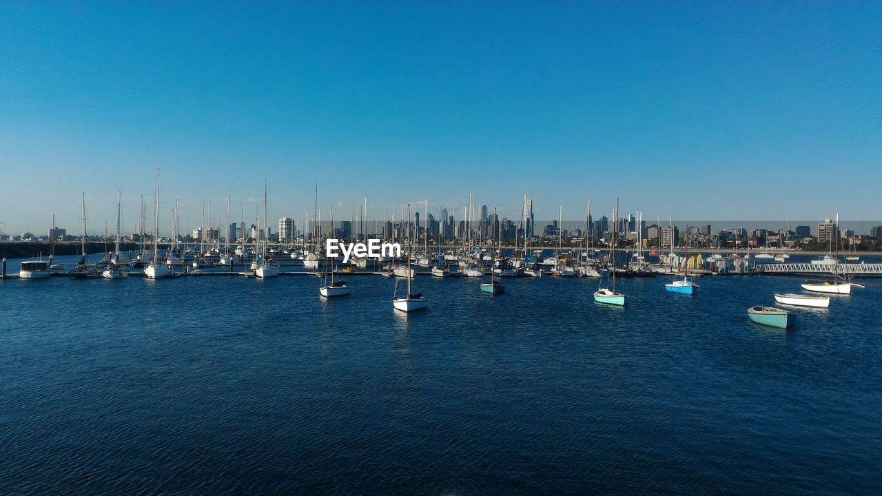 Boats in sea against clear blue sky