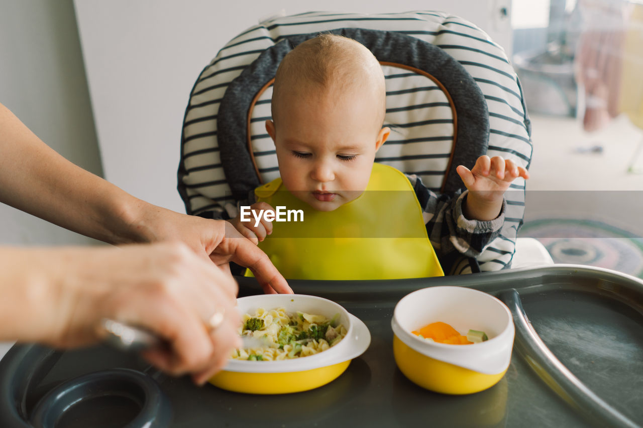 Little child with solid nutrition. baby girl eating food and mix vegetable plate