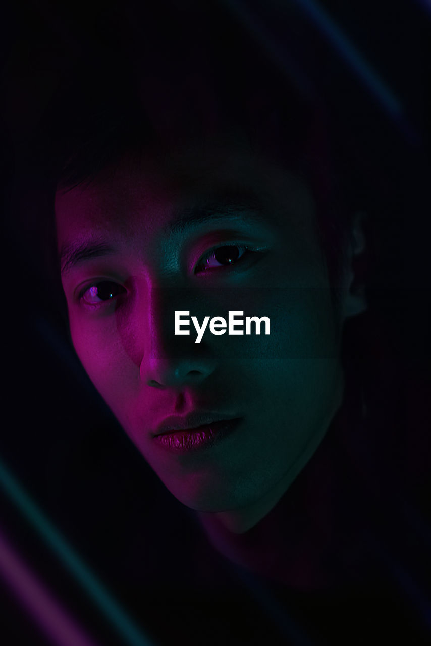 Close-up portrait of young man against black background