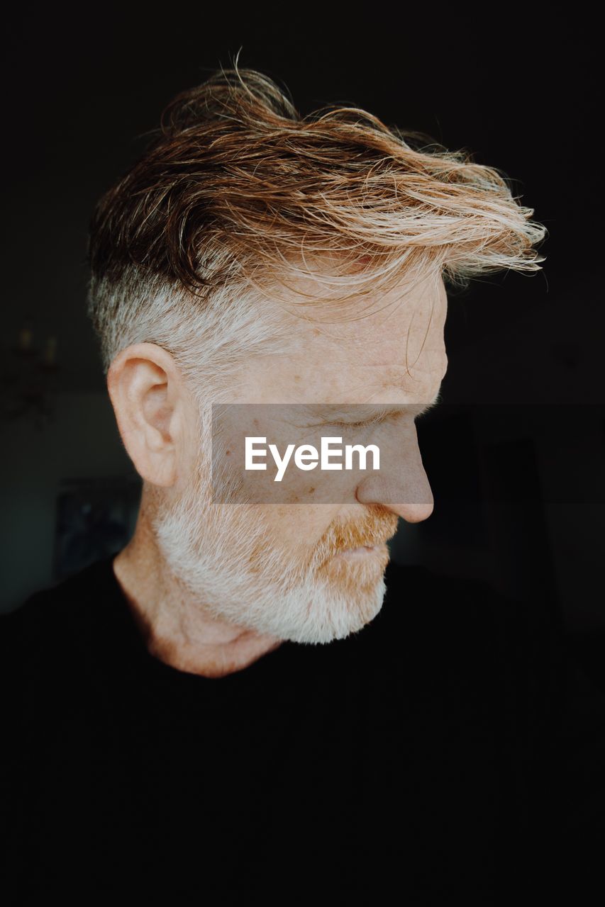 Close-up of man looking away against black background