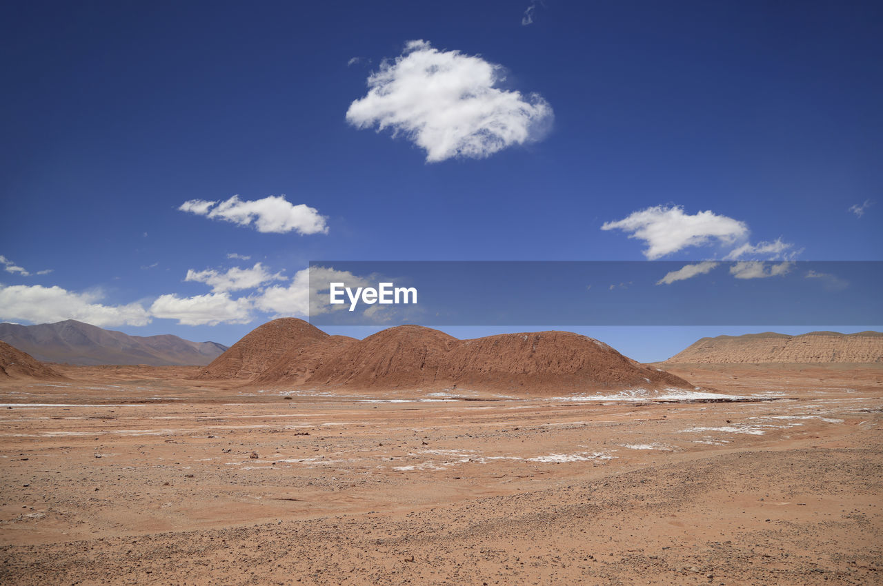 scenic view of desert against cloudy sky