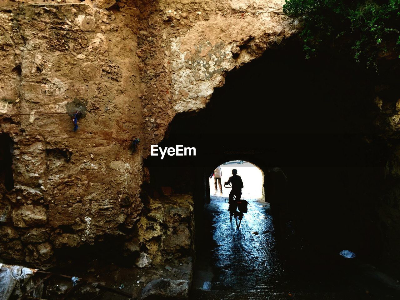 SILHOUETTE PEOPLE STANDING ON ROCK IN TUNNEL