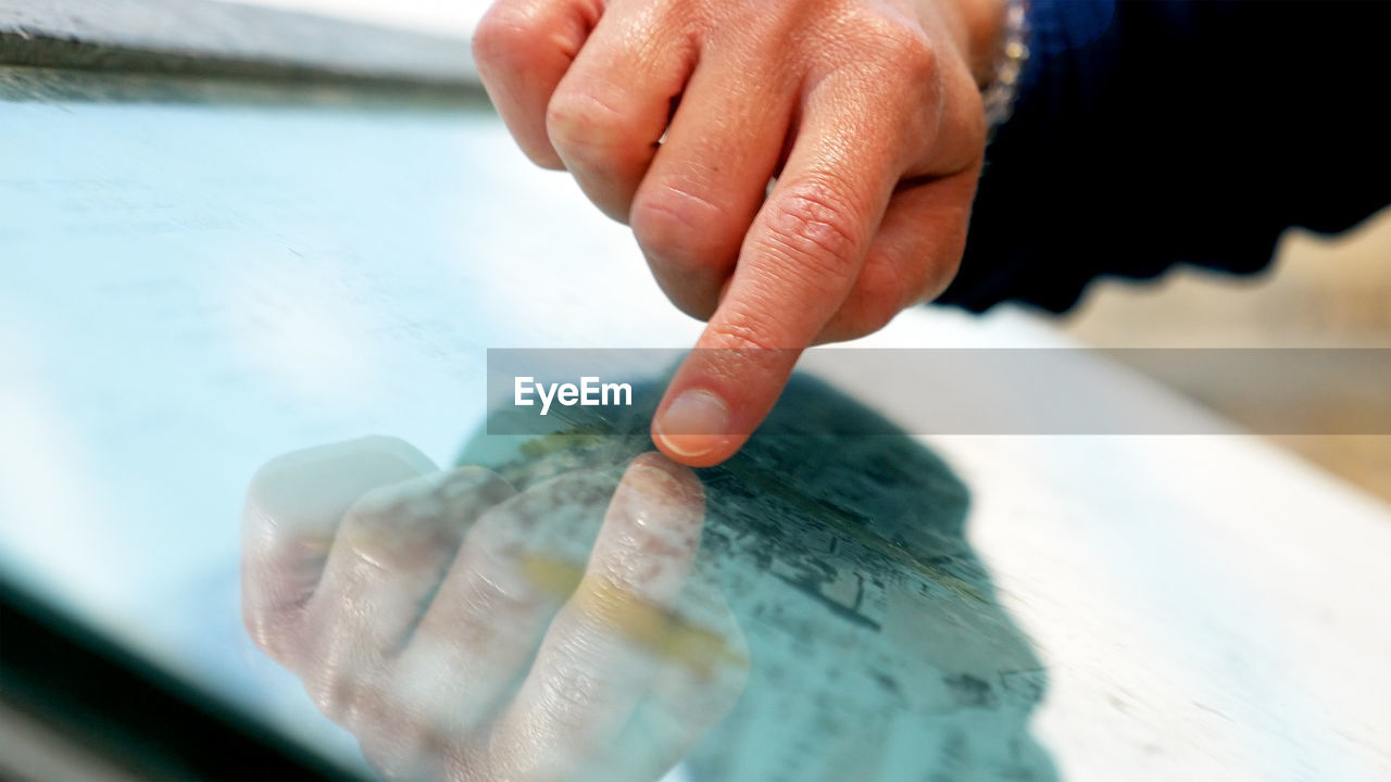 CLOSE-UP OF HAND HOLDING WATER DROP ON FINGER