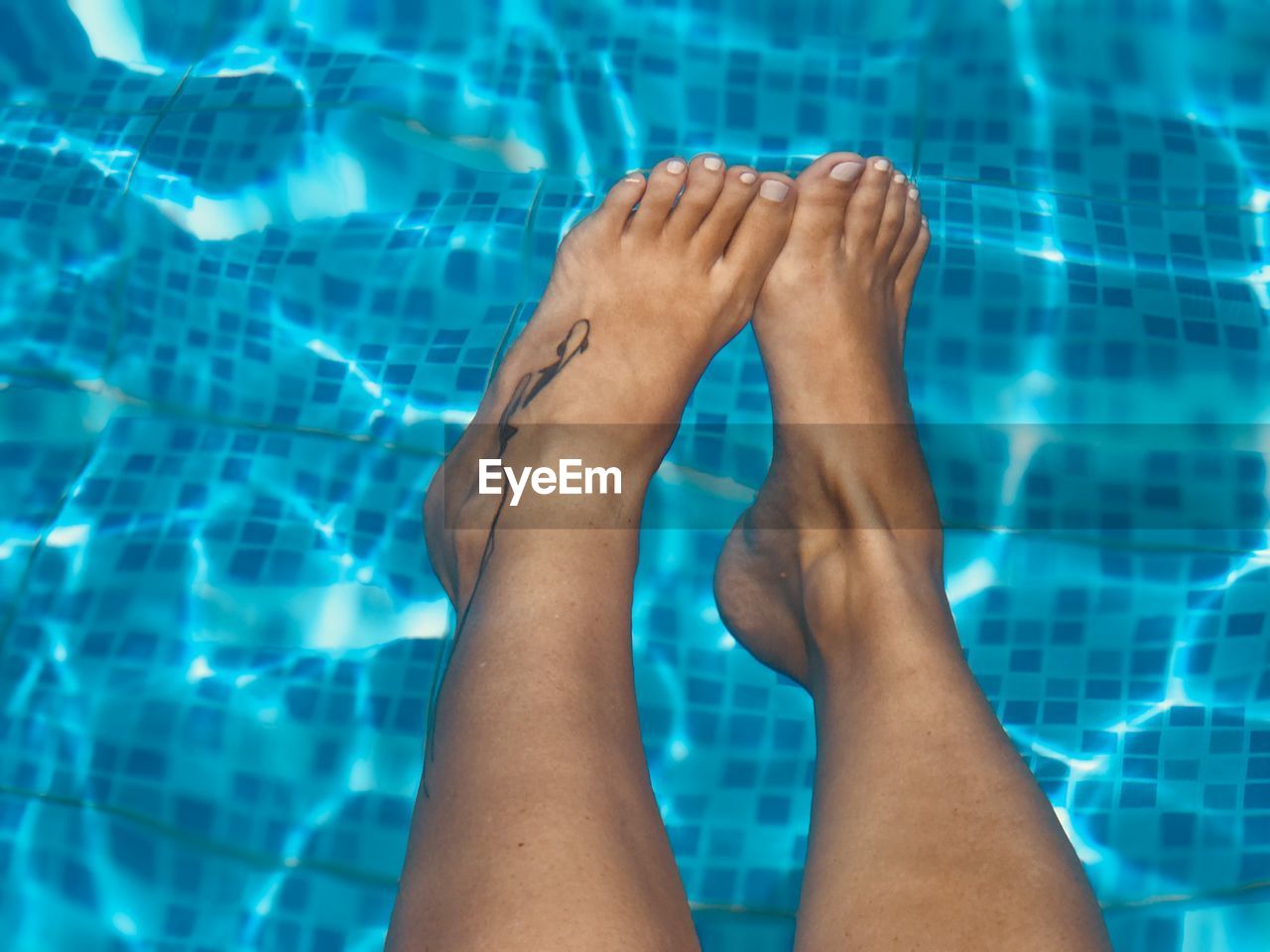 Low section of woman relaxing at swimming pool