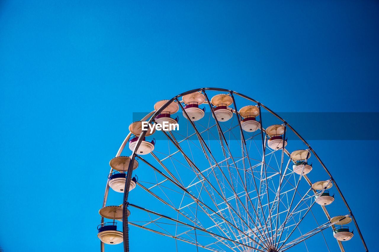 Low angle view of ferris wheel against clear blue sky