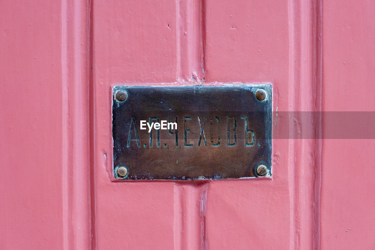 Close-up of mailbox on pink door