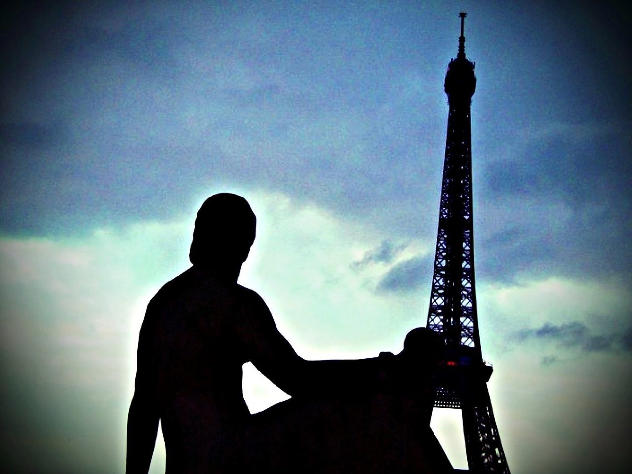 Silhouette of statue of woman sitting in front of eiffel tower