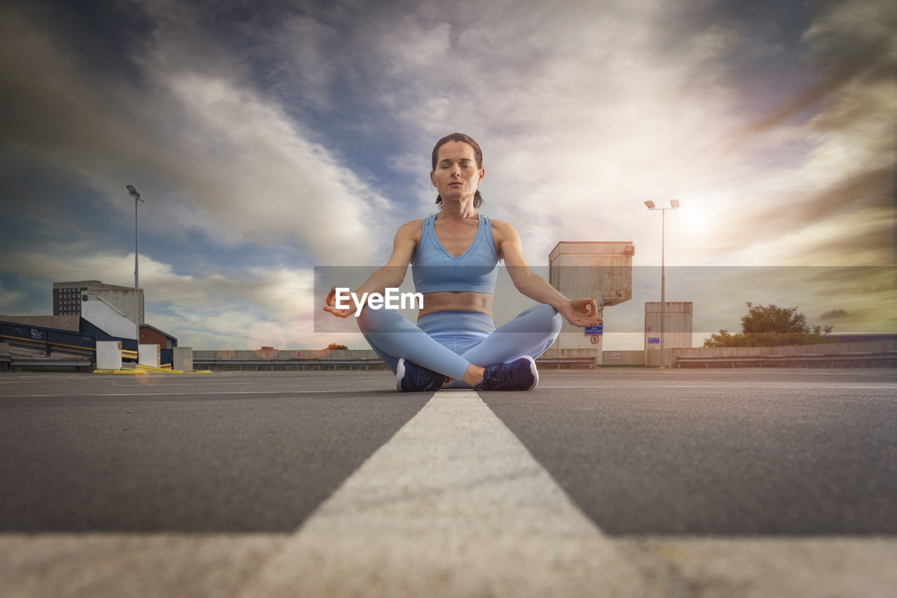 Woman sitting meditating in an urban setting, de stress.