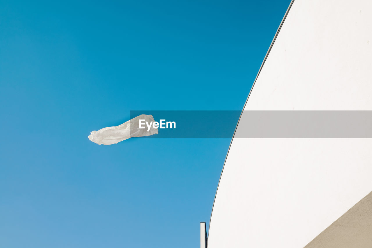 Flying empty white plastic bag in front of modern architecture