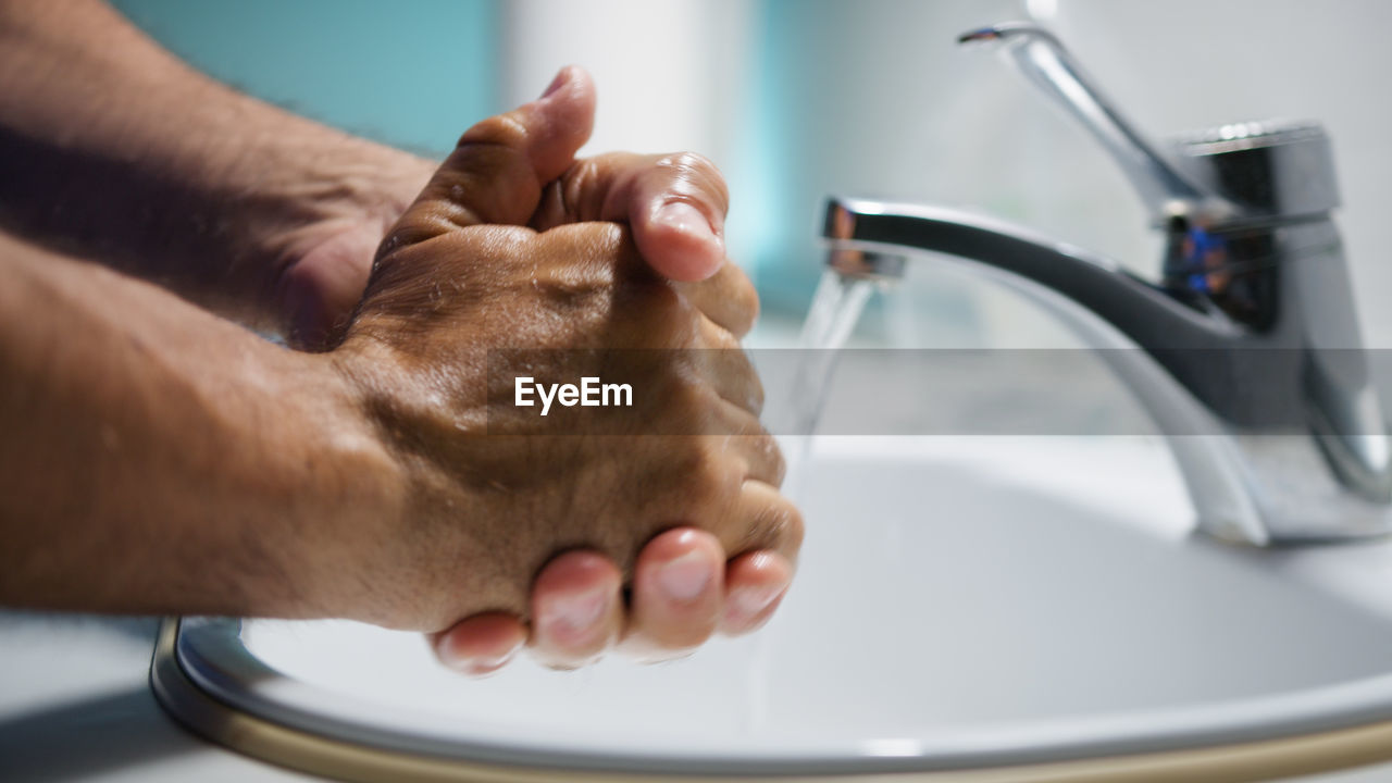 cropped image of man washing hands in sink