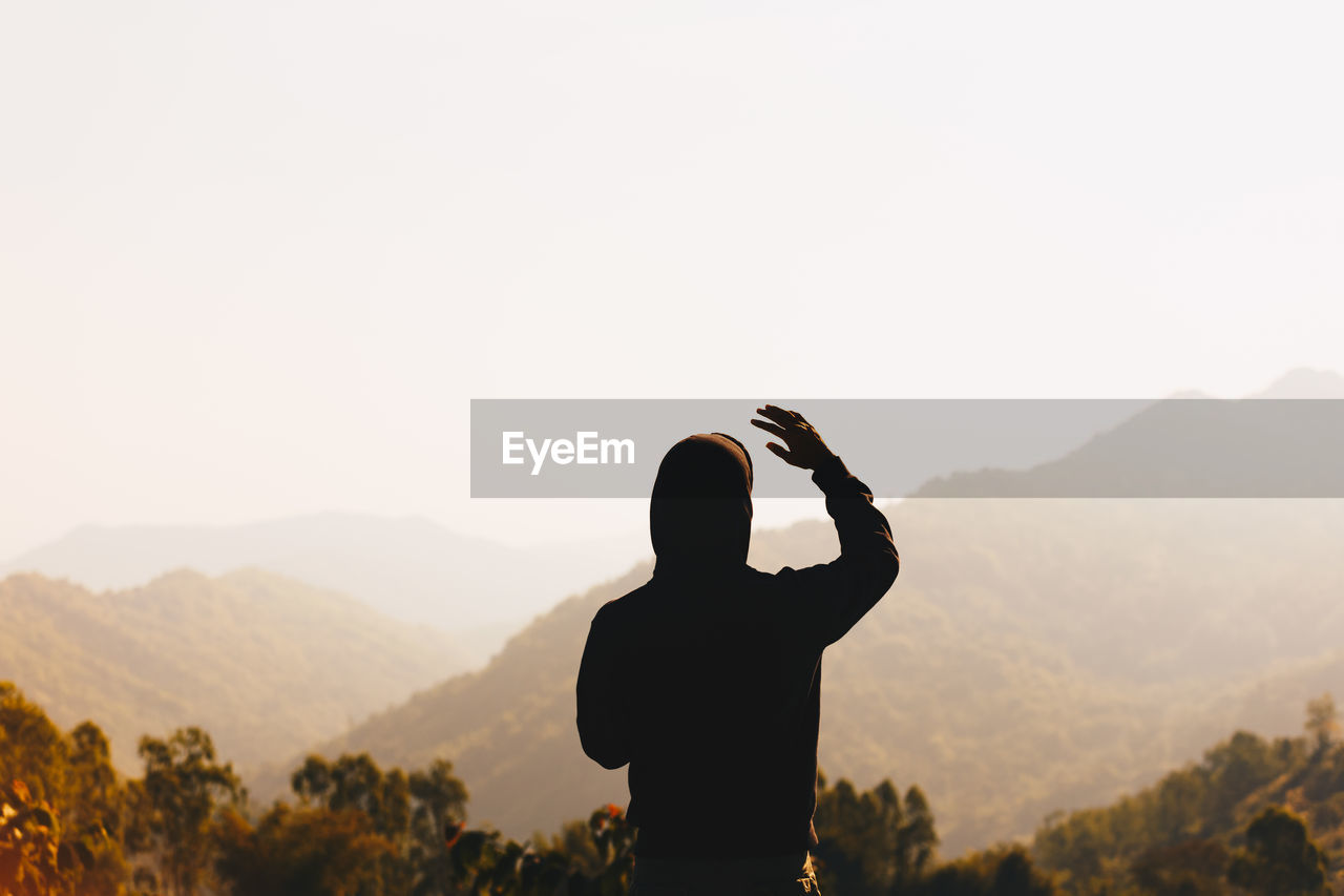 Rear view of person standing against mountain