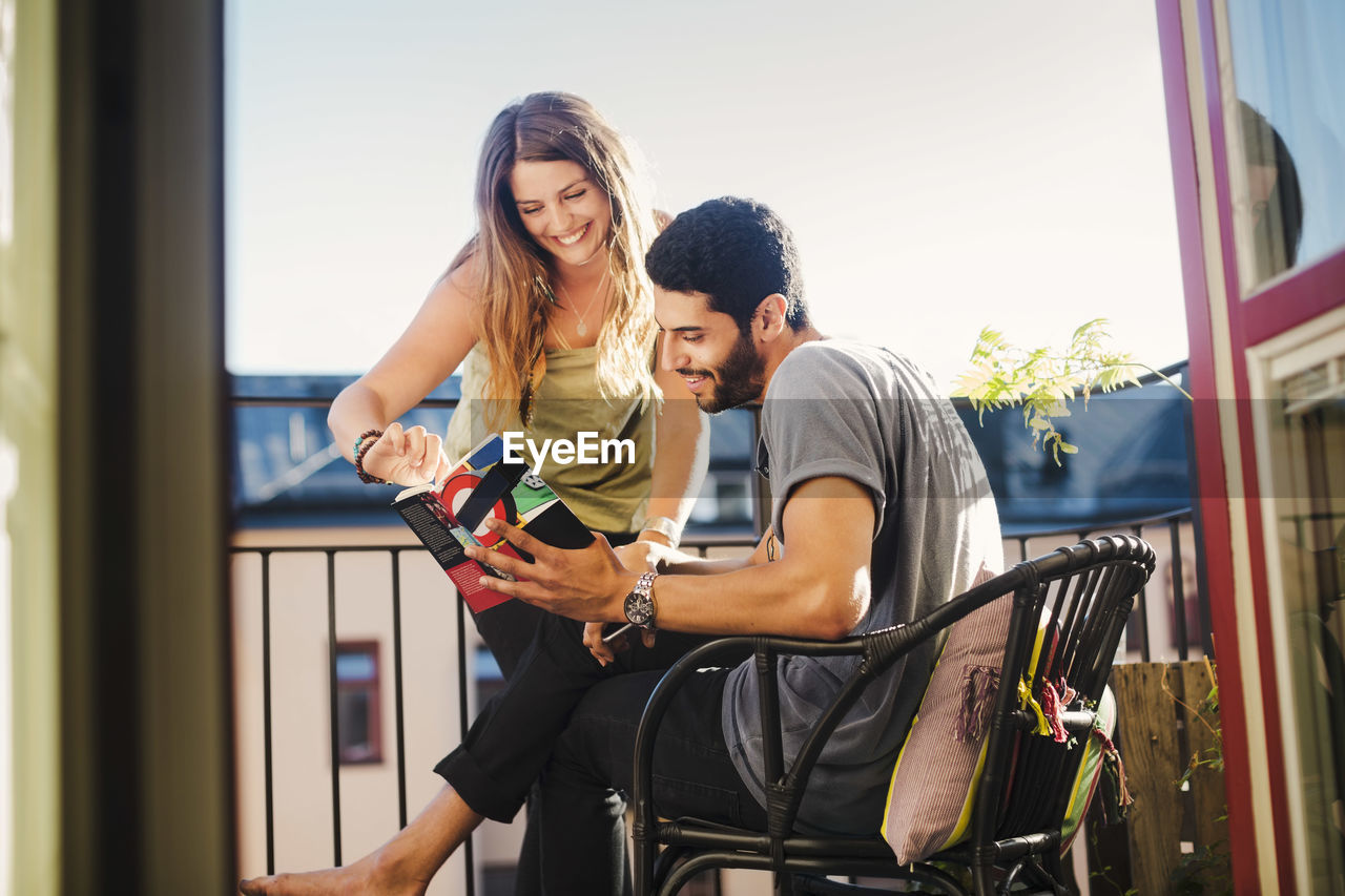 Couple reading guidebook together on balcony