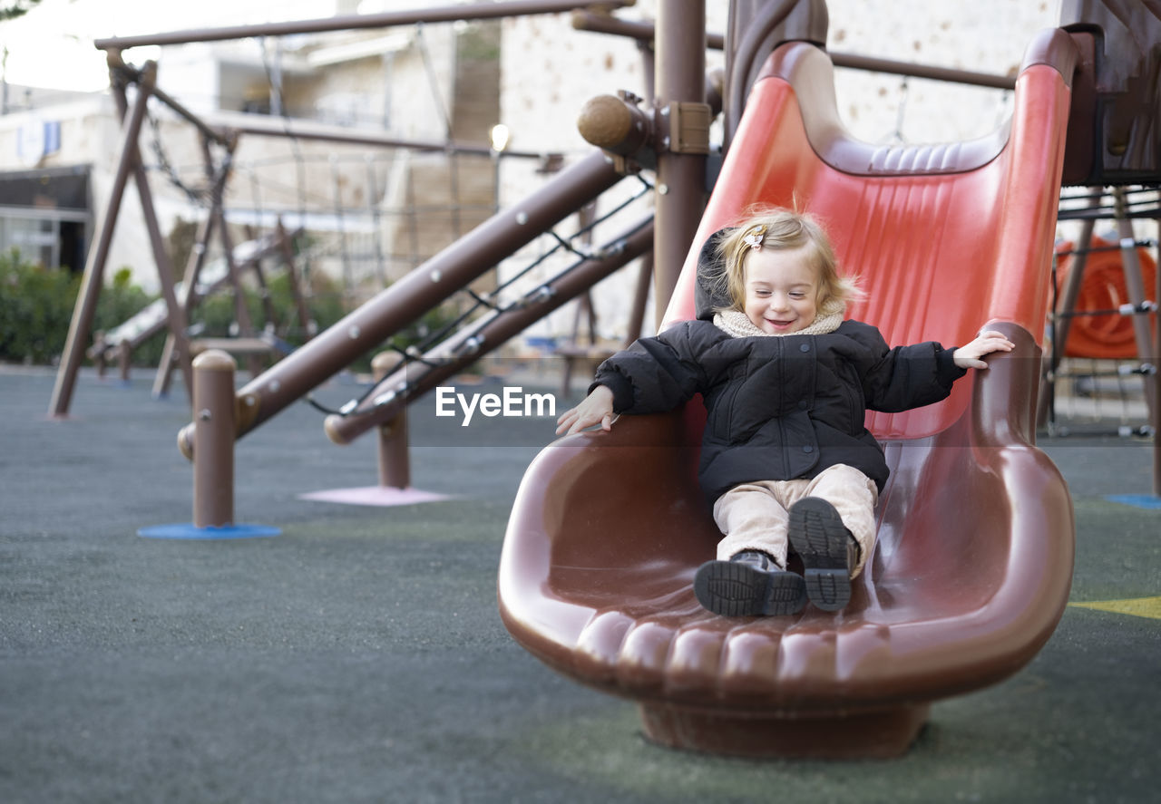 Baby girl sliding,warm clothing child,kid,toddler, infant of 1-2 year having fun in playground 