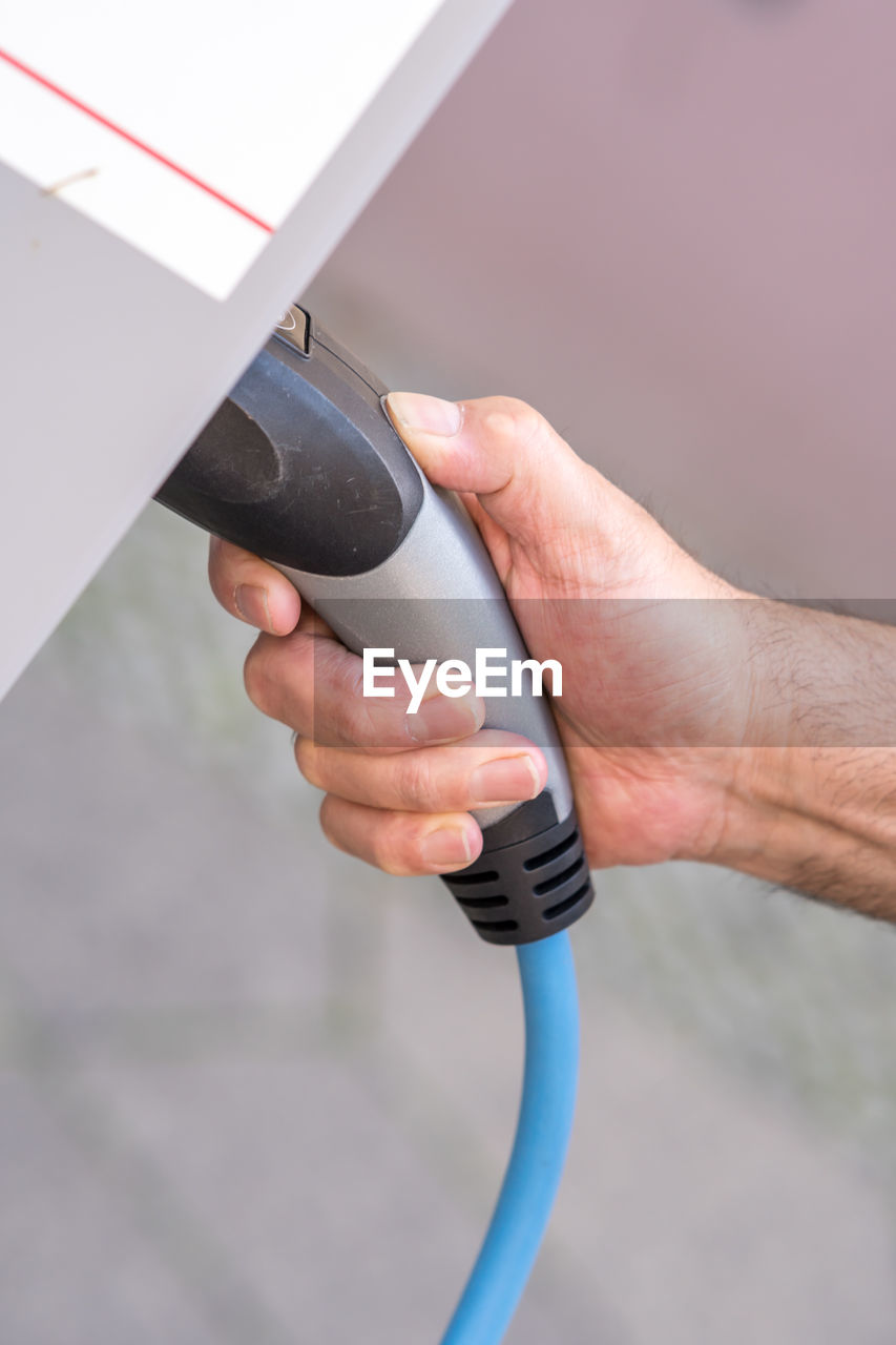 Man hand holding an electric vehicle charging connector