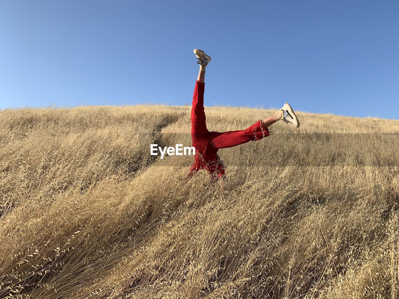 Man doing handstand on field against clear sky