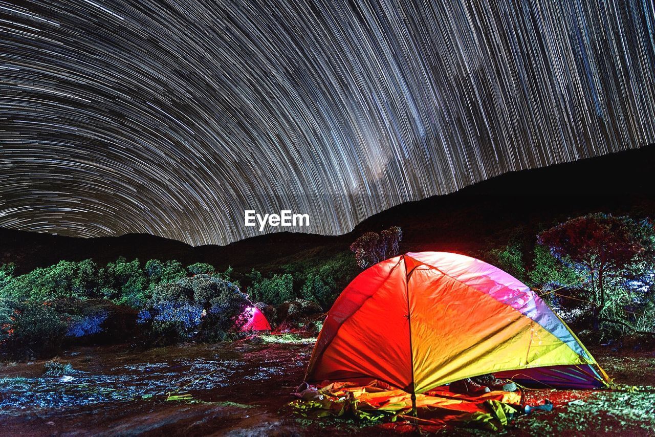 Multi colored tent against star trails at night