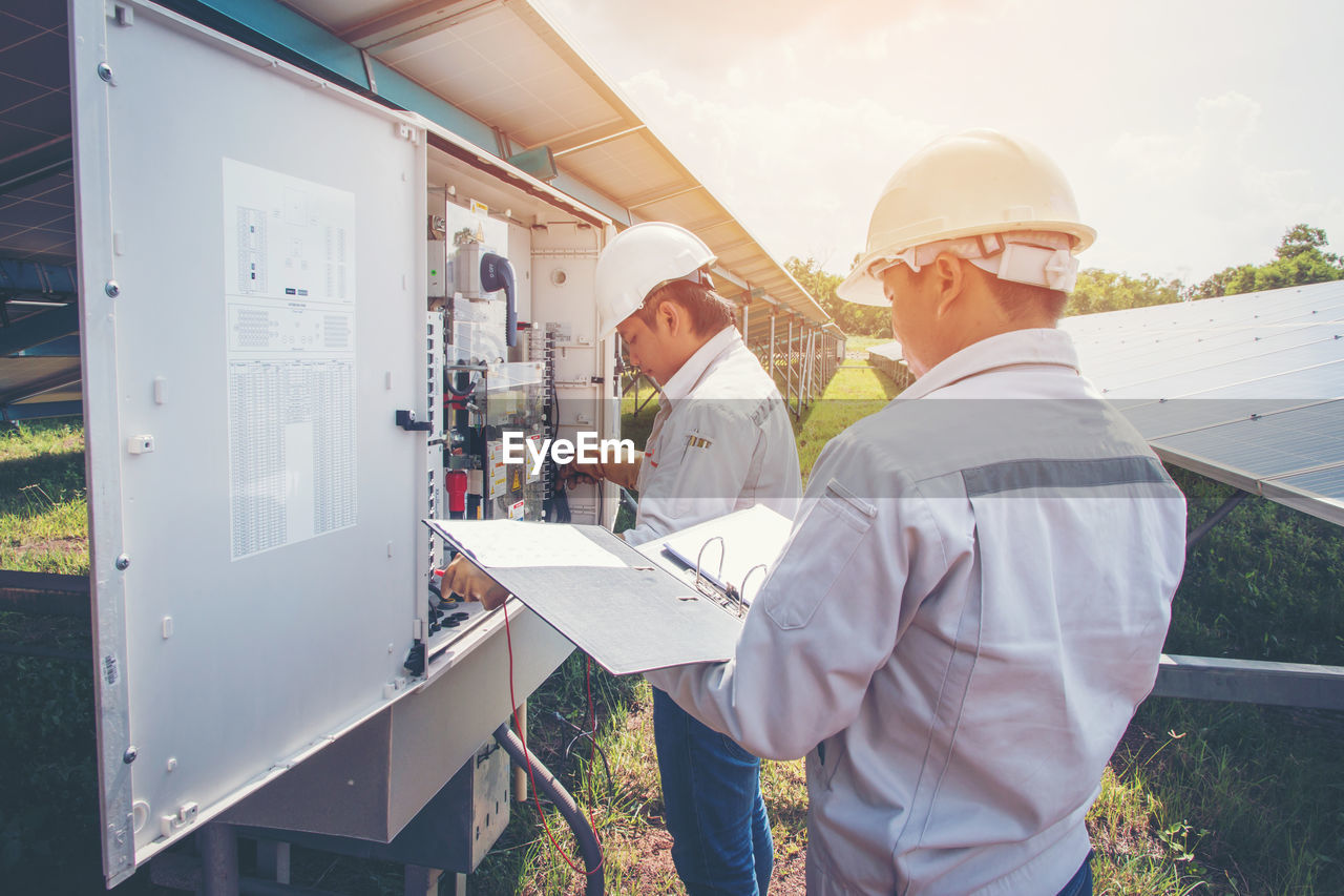 Electrical engineers working on combiner box at solar power plant