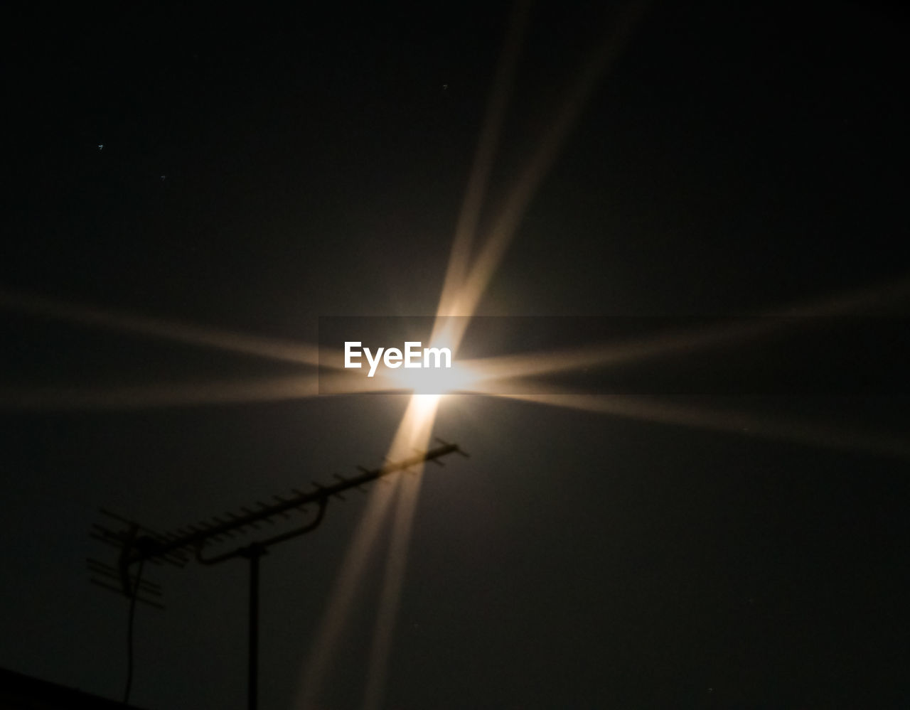 LOW ANGLE VIEW OF ILLUMINATED LIGHTS AGAINST SKY AT NIGHT