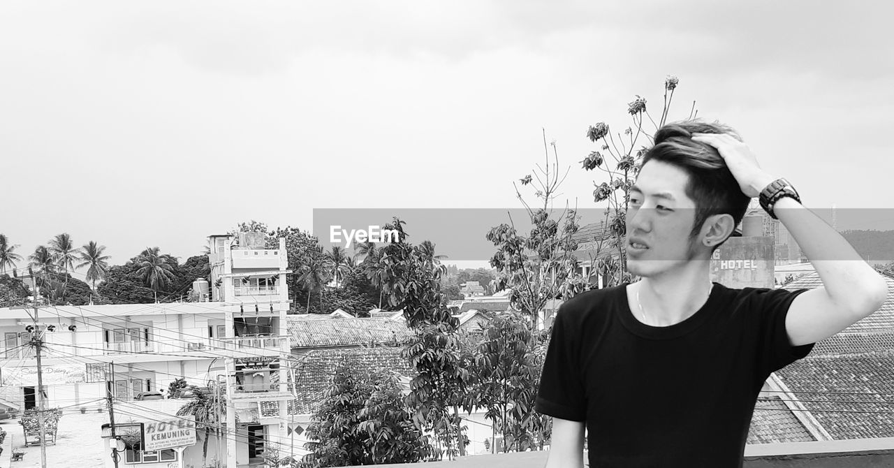 Young man with hand in hair looking away outdoors