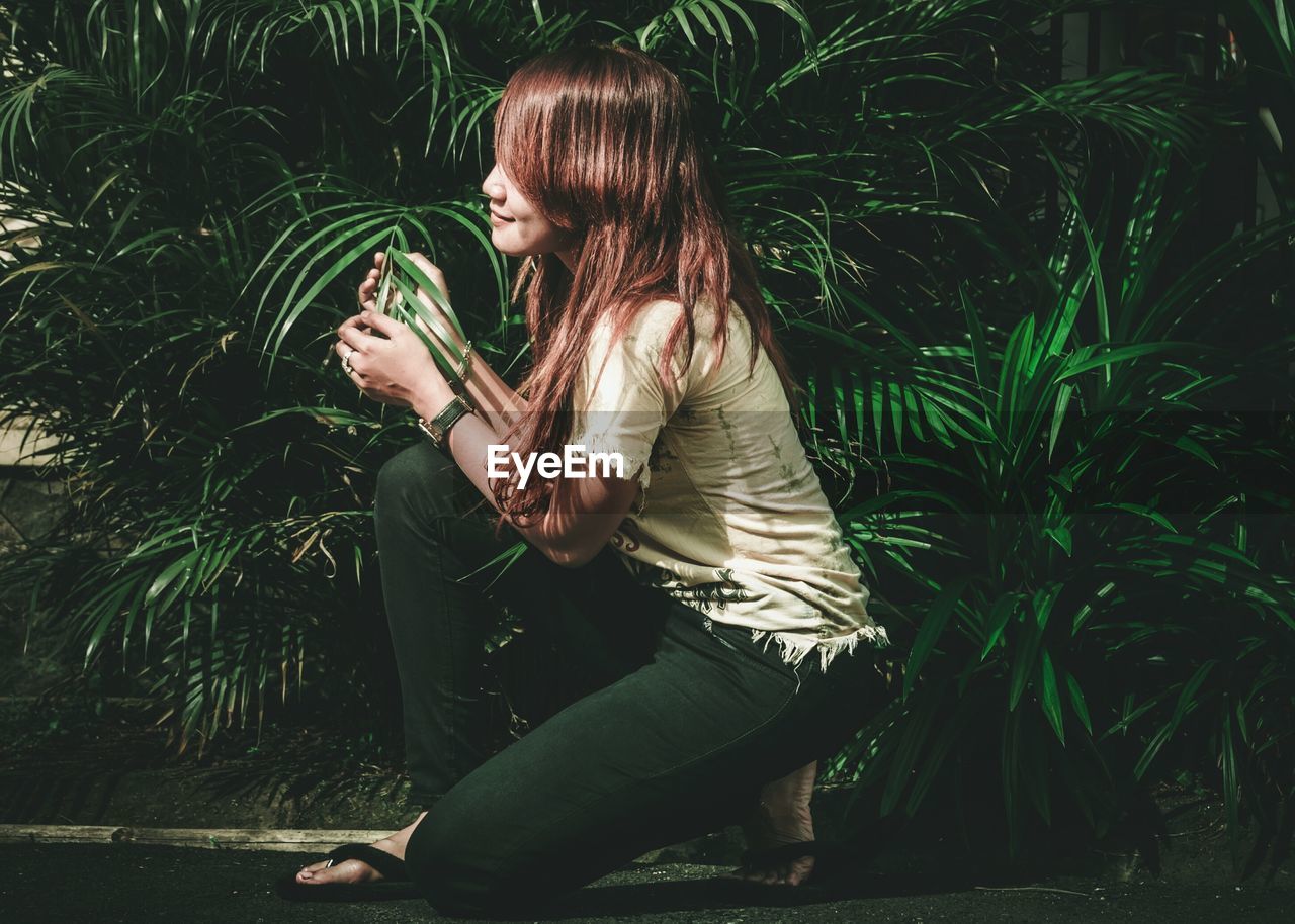 Young woman touching plant