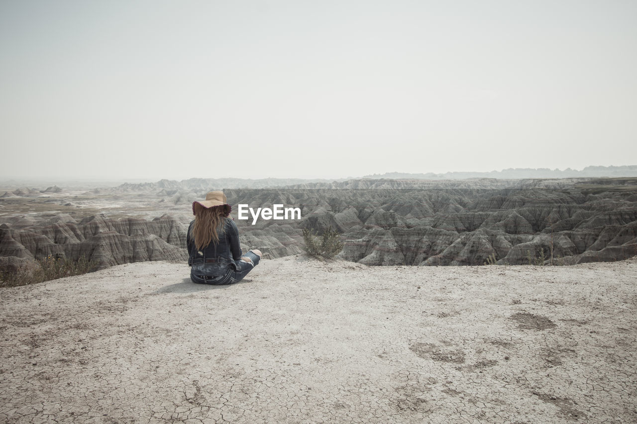 Rear view of woman looking at rocky landscape against clear sky