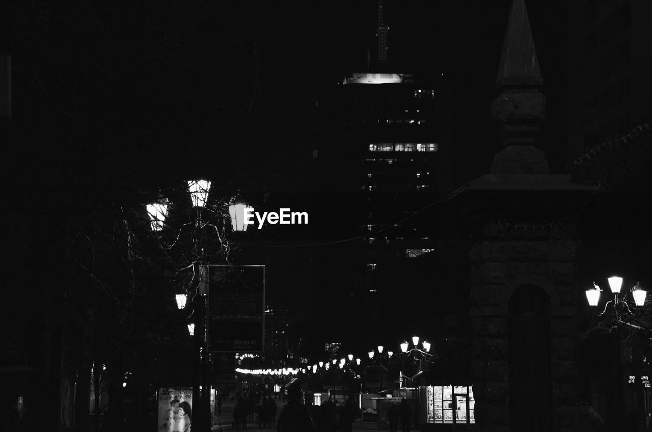 LOW ANGLE VIEW OF ILLUMINATED BUILDINGS AGAINST SKY AT NIGHT