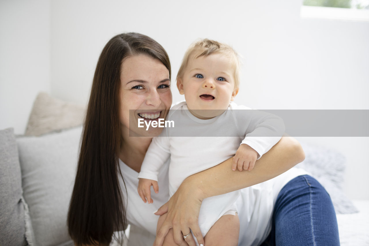 portrait of mother and daughter sitting on sofa at home