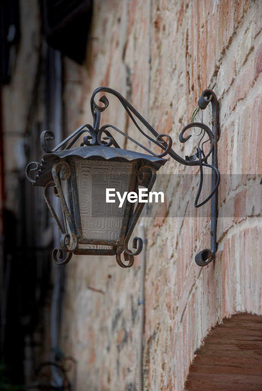 Close-up of old street light hanging on wall in san gimignano, italy