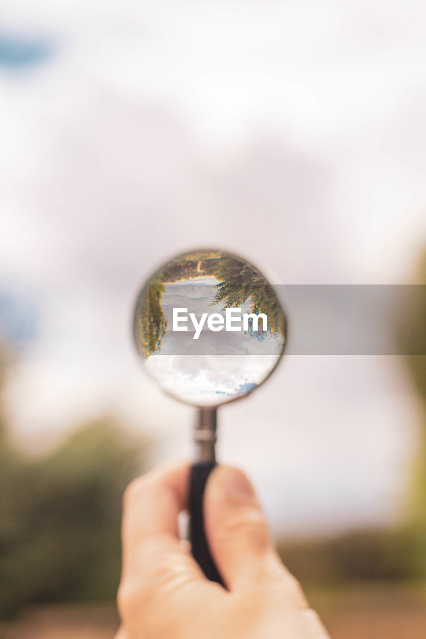 Magnifying glass pointing at cloudy blue sky