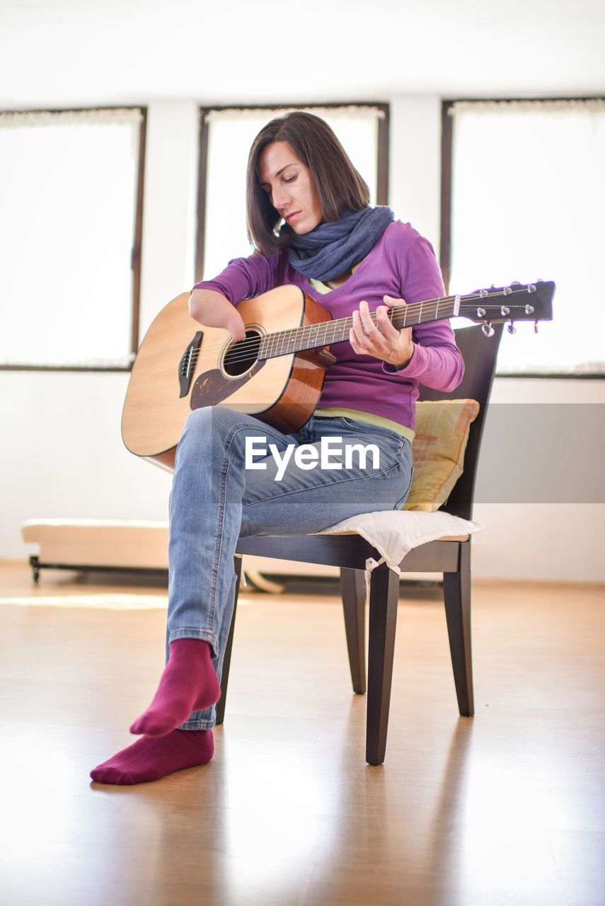 Full length of woman with disability playing guitar