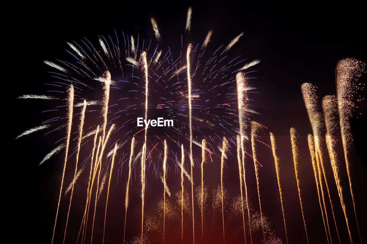 LOW ANGLE VIEW OF FIREWORKS IN NIGHT SKY