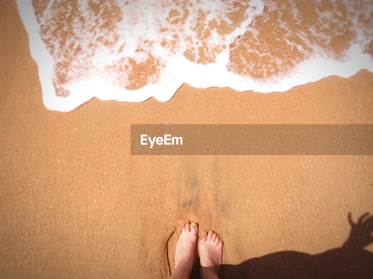 Low section of woman at beach during sunny day