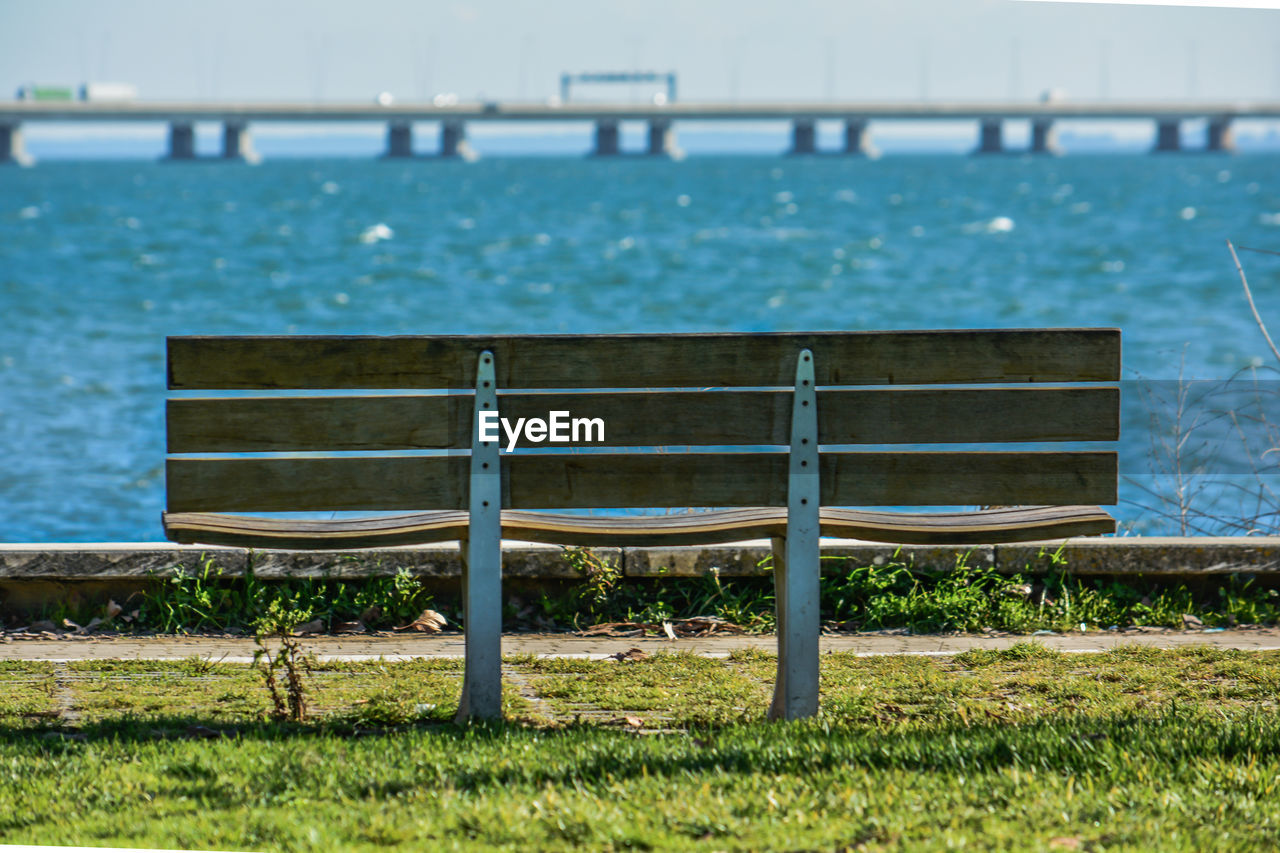 Empty bench on beach by sea