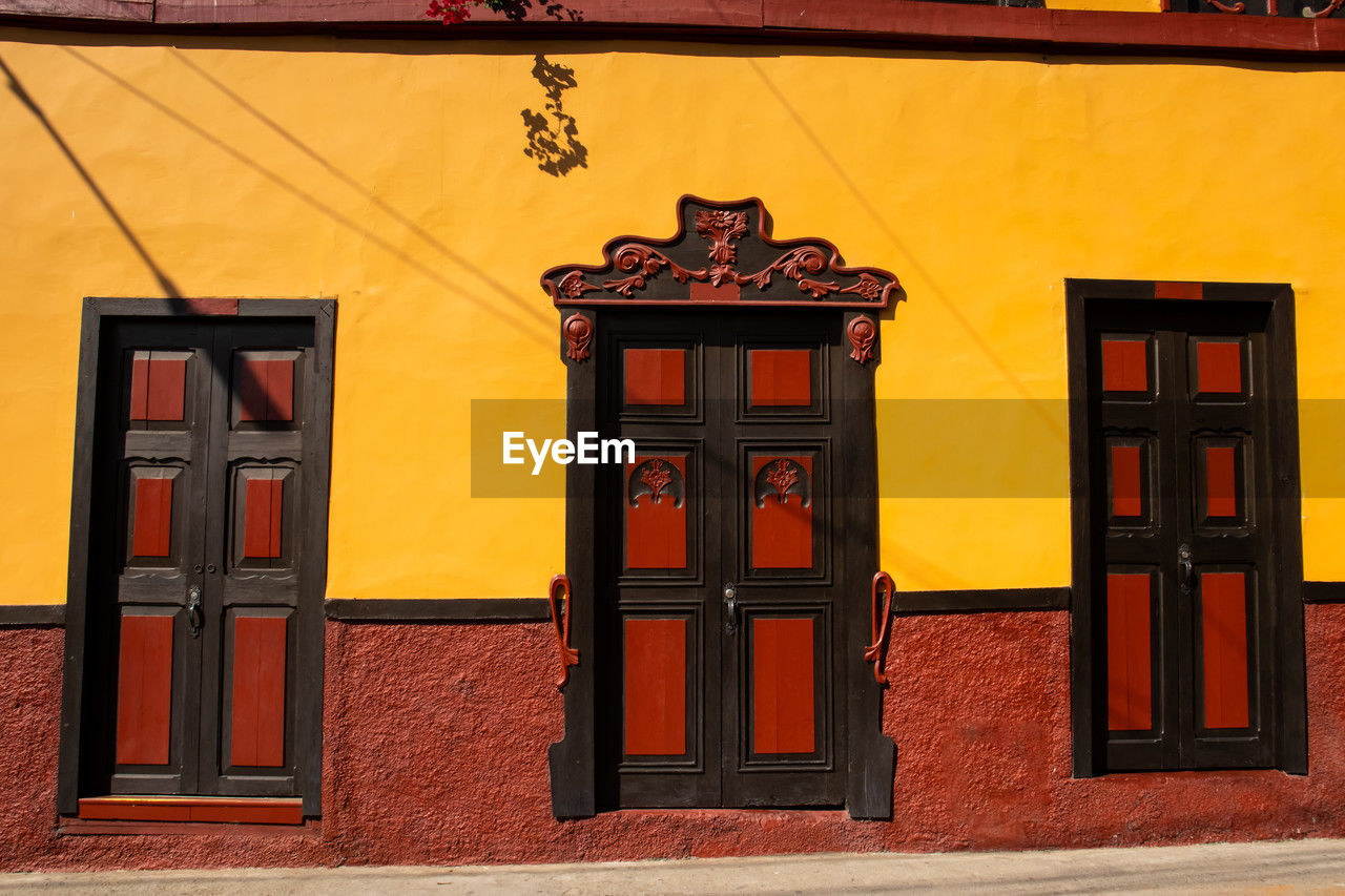 architecture, building exterior, built structure, red, no people, building, entrance, door, facade, window, city, day, wall, outdoors, travel destinations, yellow, wall - building feature, residential district, house, wood