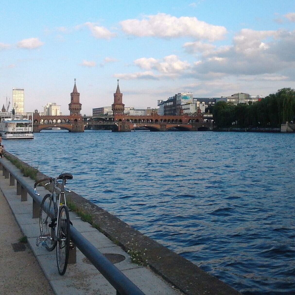 Bicycle parked by railing at river against sky