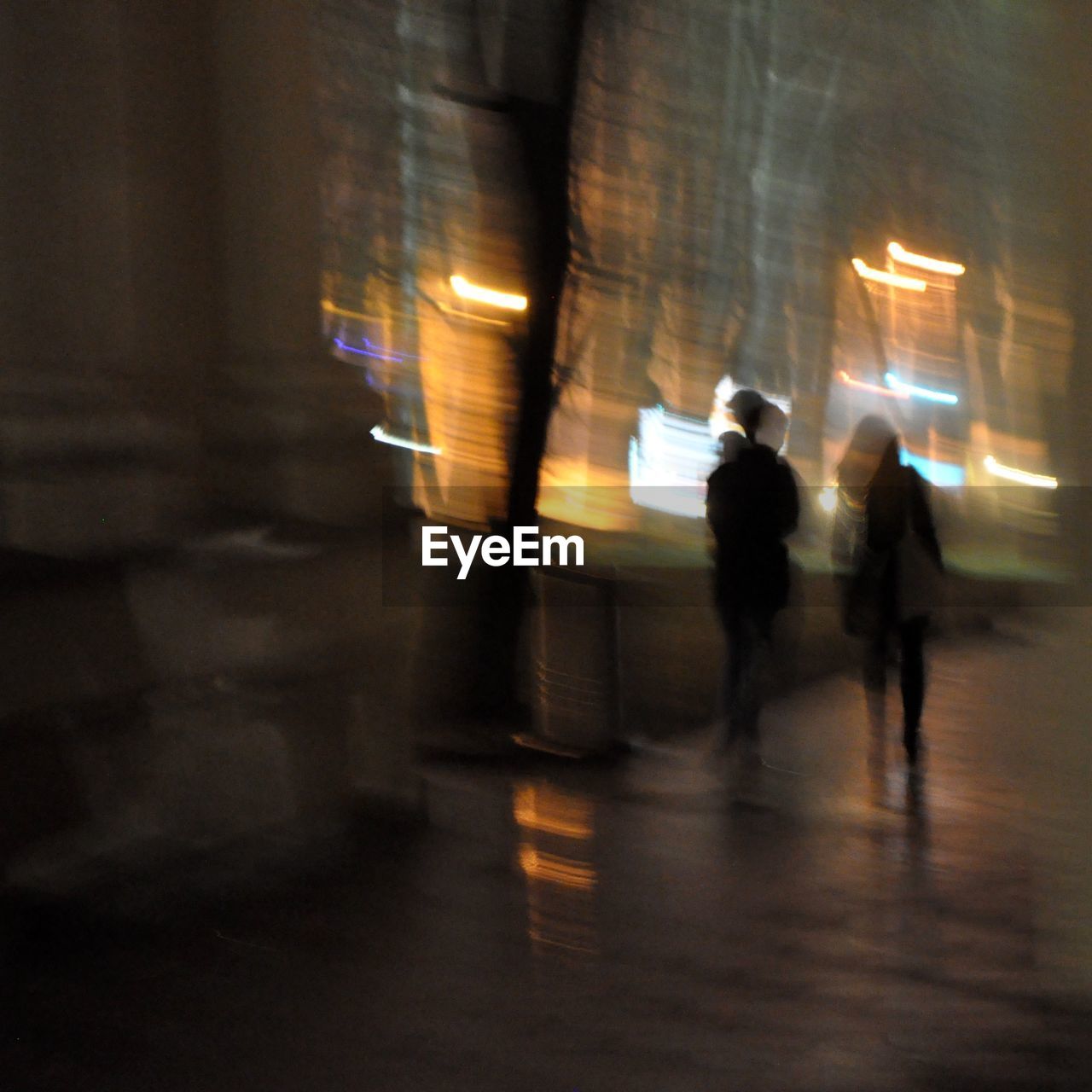 BLURRED MOTION OF PEOPLE IN ILLUMINATED CITY