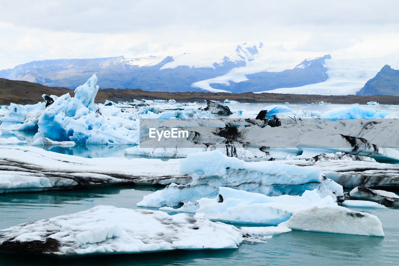 Scenic view of glacier in sea against mountains