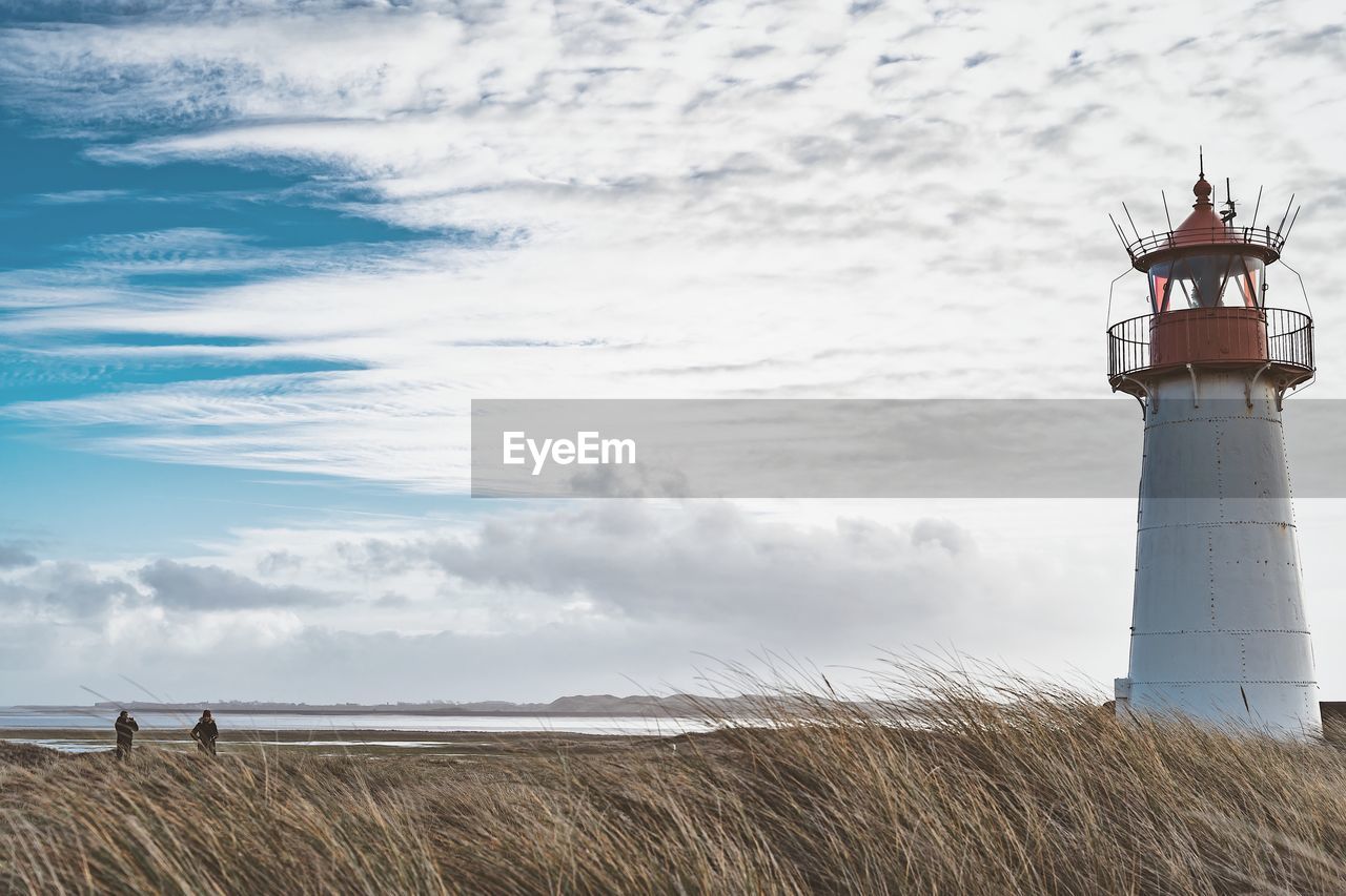 Lighthouse on field against sky