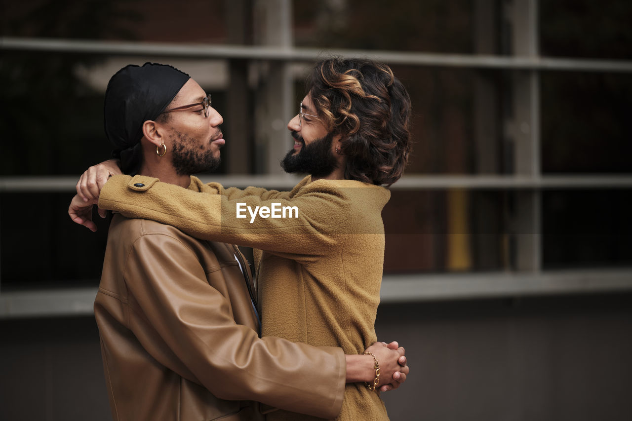 Smiling multiracial gay couple hugging each other