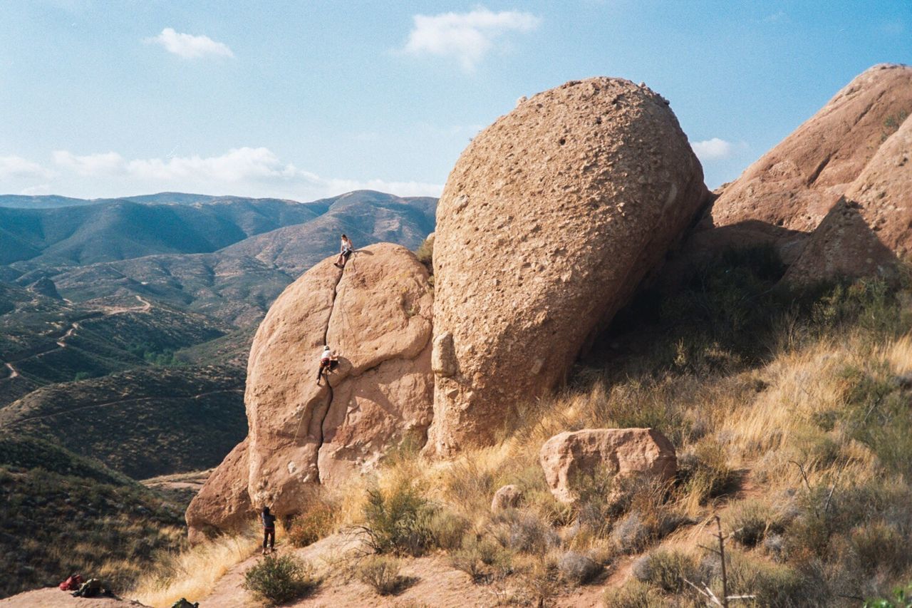 Rear view of friends climbing on rock formation