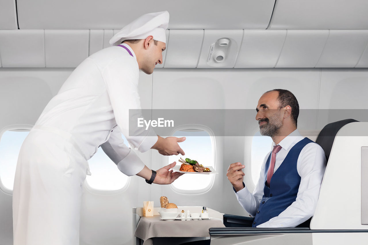 Portrait of a chef serving food to their customer in flight