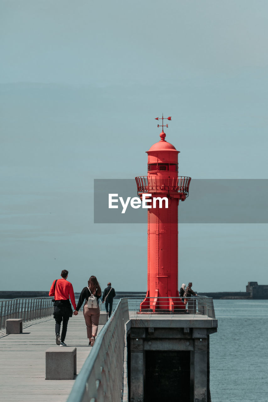 Couple walking on pier against sky
