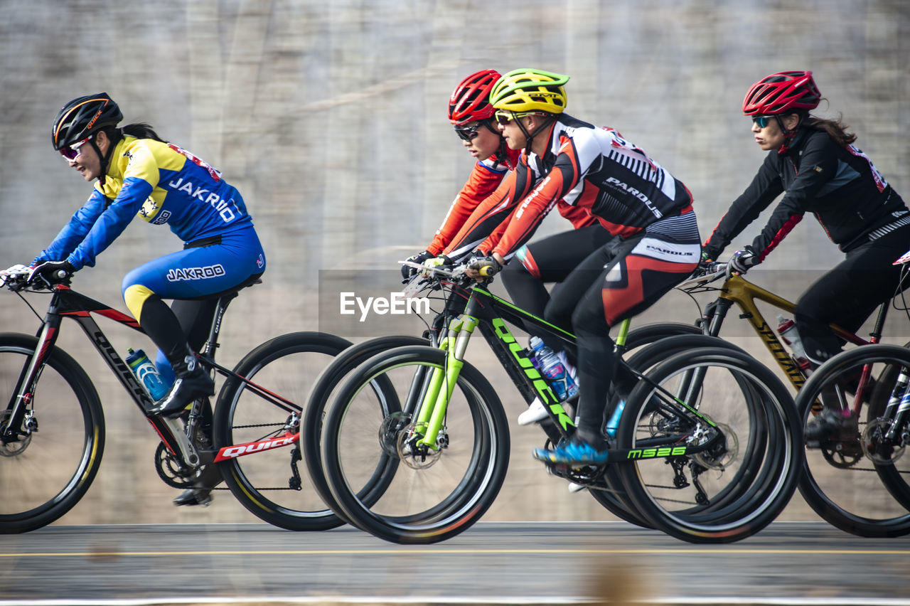 PEOPLE RIDING BICYCLES ON BICYCLE AGAINST BLURRED BACKGROUND