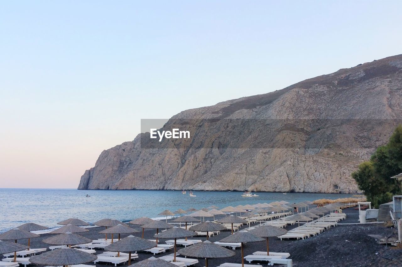 SCENIC VIEW OF SEA BY MOUNTAIN AGAINST CLEAR SKY