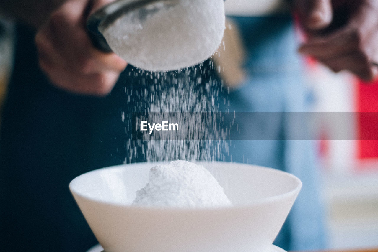 Midsection of person sifting flour 