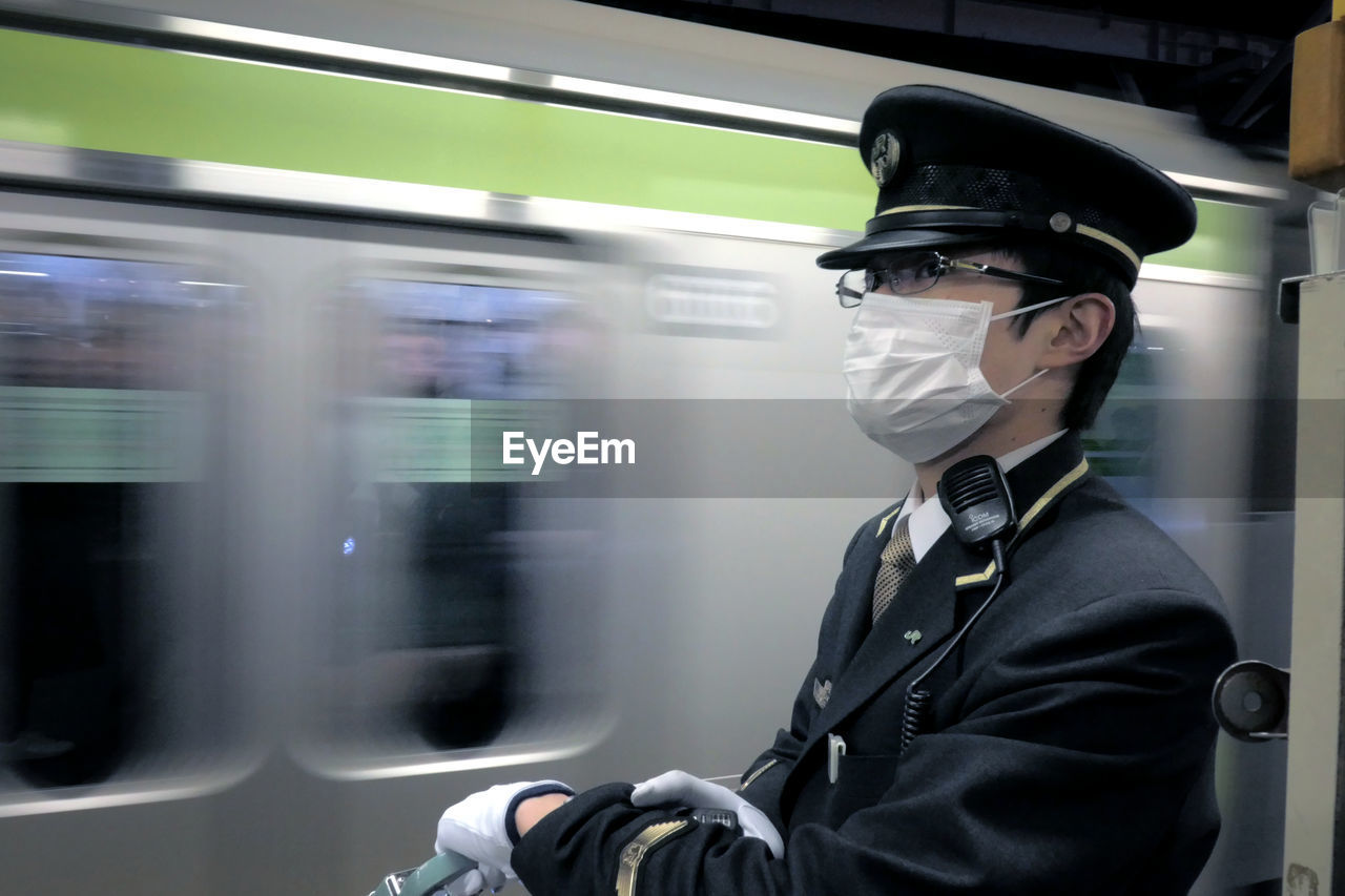 CLOSE-UP OF MAN STANDING BY TRAIN