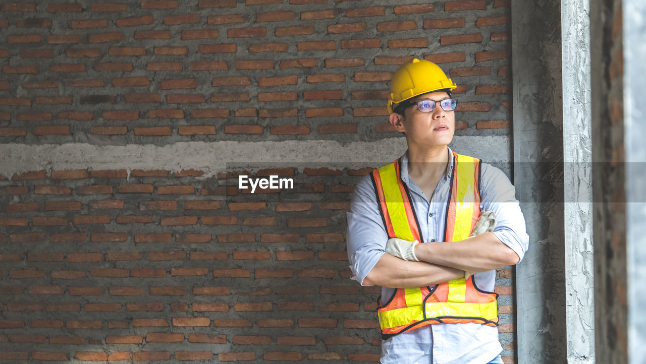 LOW ANGLE VIEW OF MAN WORKING ON BRICK WALL