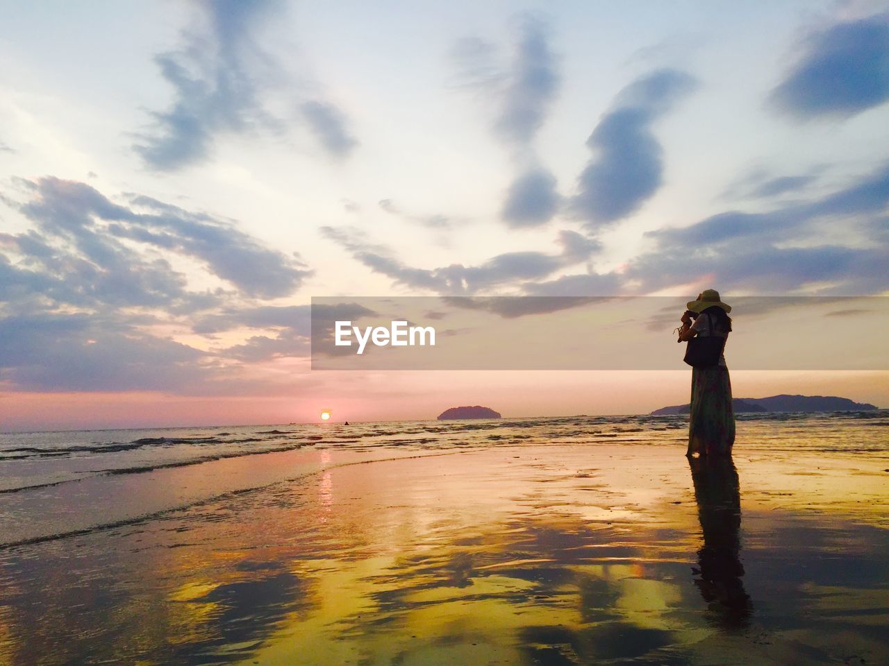 Woman taking photograph of sunset