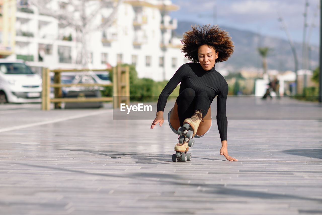 Young woman roller skating on sidewalk in city